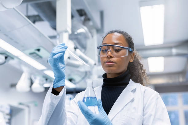 donna scienziata che sperimenta con sostanze chimiche in laboratorio - beuta foto e immagini stock