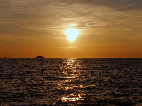 Silhouette of ship in the sea in orange sunset