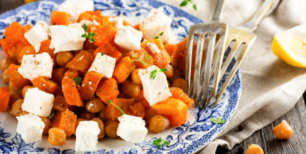 ensalada tibia de calabaza, garbanzos y queso feta sobre el viejo fondo de madera. enfoque selectivo. - pumpkin simplicity rustic old fotografías e imágenes de stock