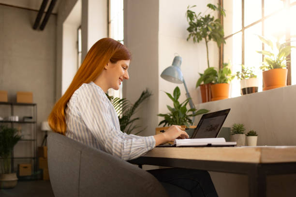 Side view of a successful Caucasian woman working from home on a laptop stock photo
