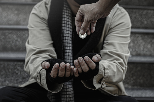 Close-up of the poor or homeless Homeless people ask for money in public. The poor beggar in the city sat on the stairs with a silver mug.