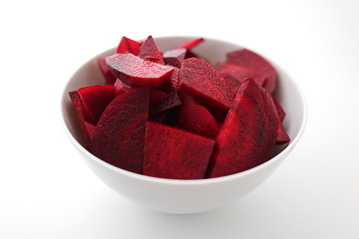 Fresh beetroot sliced ​​in a white porcelain bowl against a white background