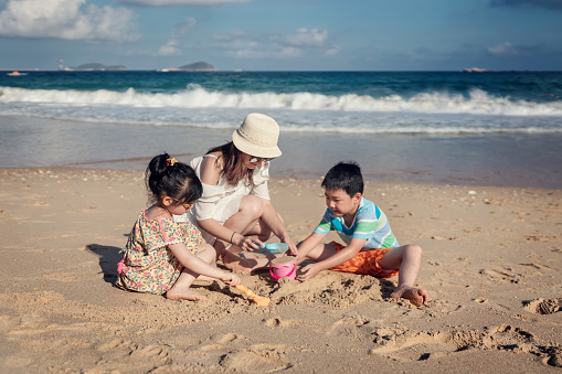 Mother and her children building a sandcastle together