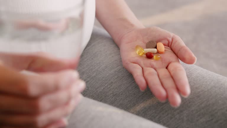 Close-up Pregnant Woman Hands Holding pill and glass of water at home.