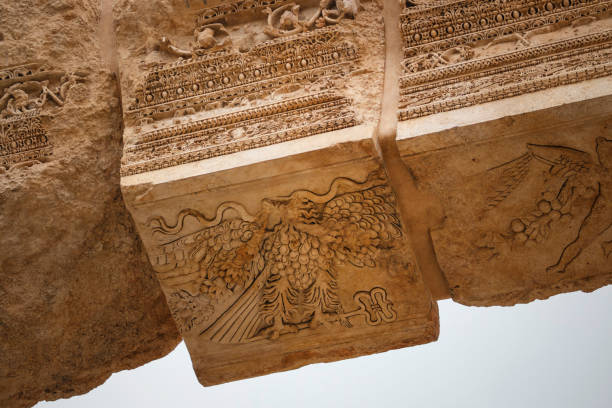 cupid figure and an eagle holding a herald's staff carved at the entrance of bacchus temple, heliopolis roman ruins, baalbek, lebanon - baalbek imagens e fotografias de stock