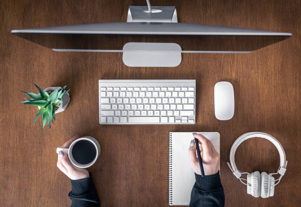 istock Top view, woman working at the computer, wooden table. 1366616069