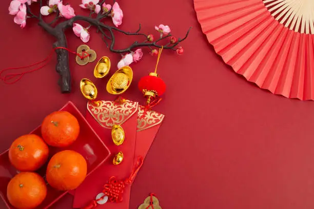 Photo of Chinese new year festival decorations. Orange, red packet, plum blossom and lucky money. Translation: let ten thousand wishes come true.