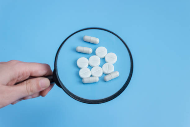 istock Medical pills under a magnifying glass on a blue background 1366616622