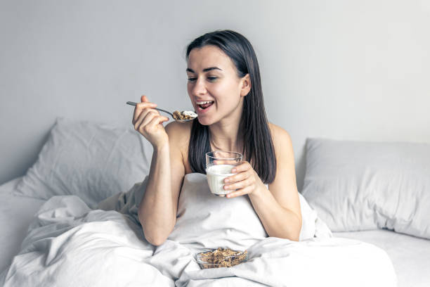 istock A young woman in white bed with cereal and milk. 1366618202