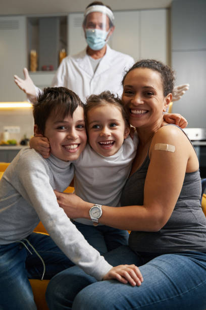 istock Happy family smiling to camera with doctor behind them 1366618341