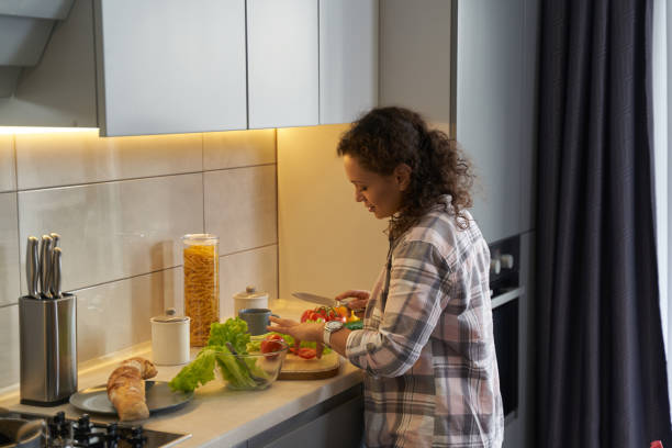 istock Woman in kitchen cooking salad on table 1366618361