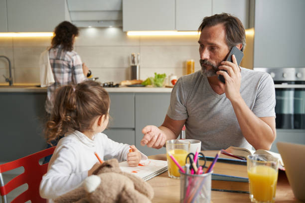 istock Girl drawing in notepad while father talking on smartphone 1366618372