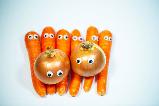 istock Onions and carrots with eyes on a white background 1366619172