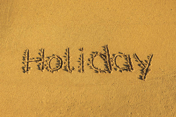 The word holiday written in the sand