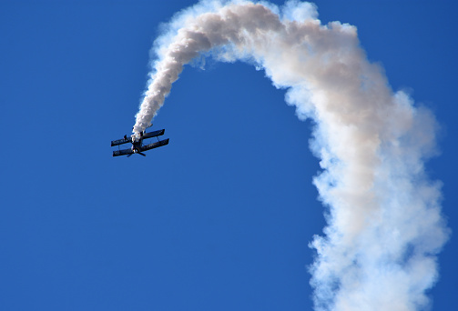 Little  Gransden,  Cambridgeshire, England - August 25, 2019:  Pitts Model 12  stunt byplane performing   with smoke trail and blue sky.