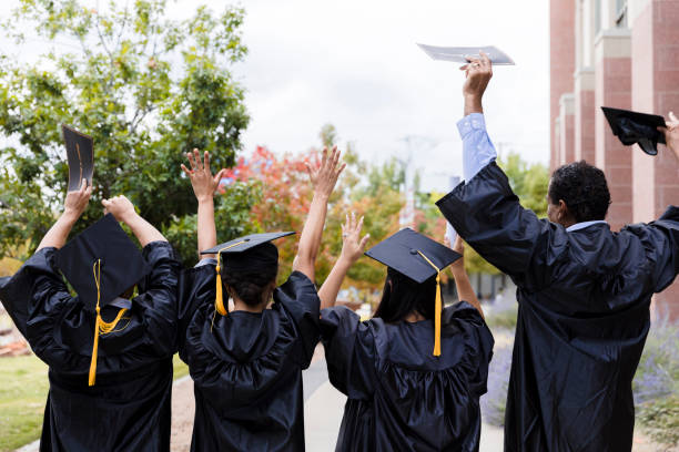 istock Rear view four graduates cheering after graduation 1366623762