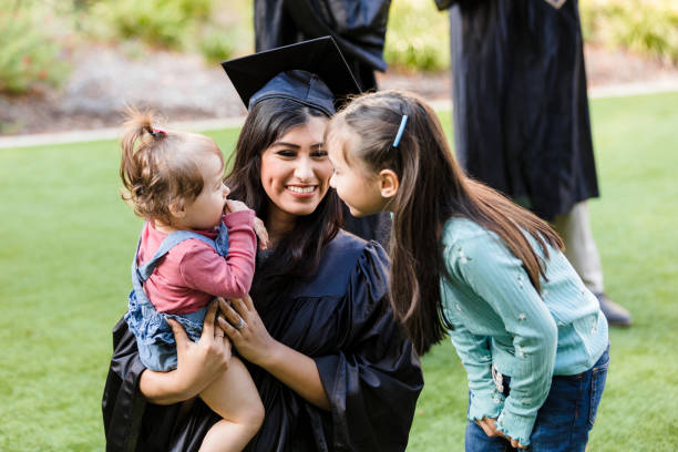 istock Elementary age sister talks to baby held by graduate 1366623867