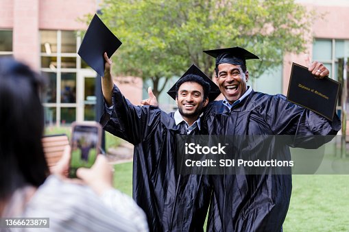 istock Male graduates cheer while posing for photo 1366623879