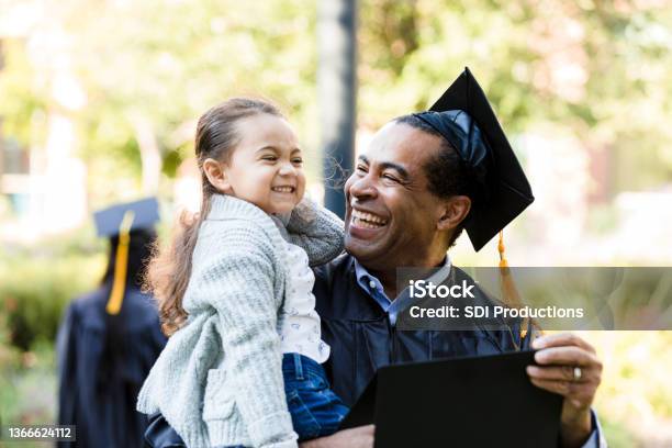 Little girl makes graduating grandfather laugh with silly face
