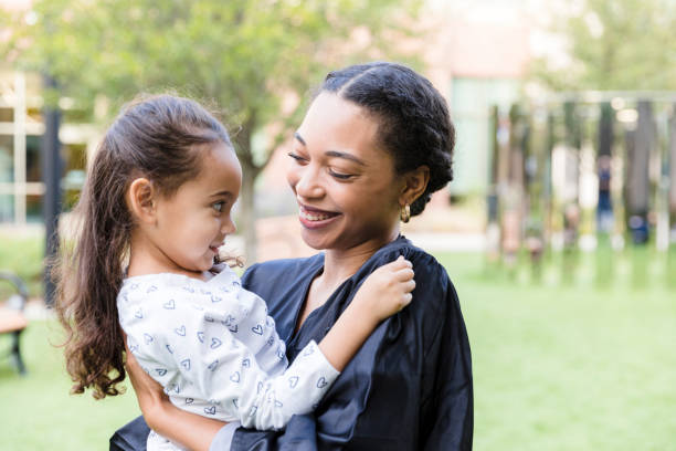 istock Female college graduate holds young daughter 1366624241