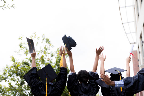 認識できない多民族の卒業生グループが腕を上げて歓声を上げる - cheering arms raised women university ストックフォトと画像