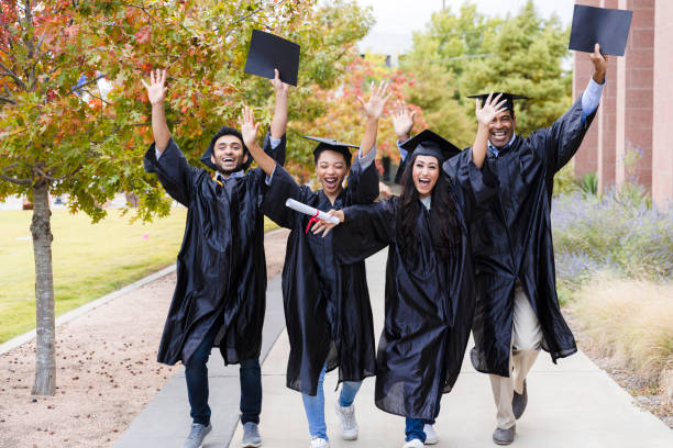 istock Four diverse friends walk and cheer after graduation ceremony 1366624427