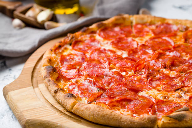 istock Pepperoni pizza on wooden board on grey table macro close up 1366624441