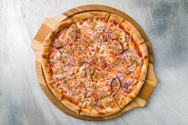 グレーのテーブルトップビューのボード上にマグロと赤玉ねぎとピザ - pizza tuna prepared fish cheese ストックフォトと画像