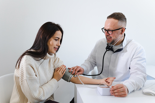 Male doctor at the medical examination measures the blood pressure of a woman patient. Woman on appointment in cardiologist