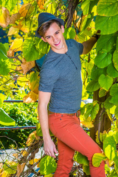 istock a young handsome guy is standing by green plants, looking at you.
