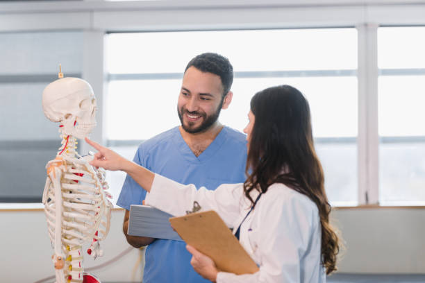 istock Male medical student smiles while learning about human skull 1366626301