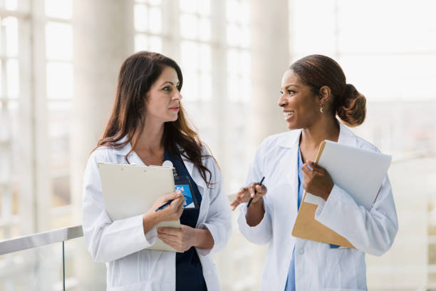 Female healthcare professionals walk and talk together stock photo