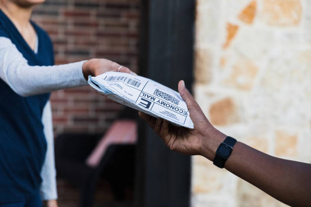 Standing on the front porch, the unrecognizable work from home woman receives a package from an unrecognizable delivery person.