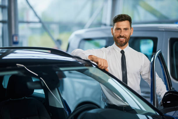 istock Handsome man posing near luxury car at showroom 1366627665