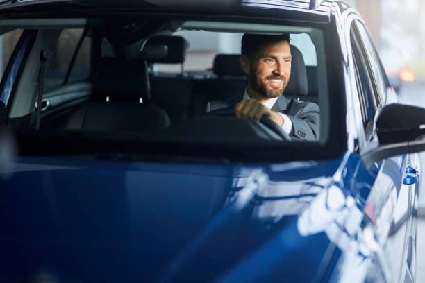 istock Smiling man in suit testing car at modern salon 1366627727