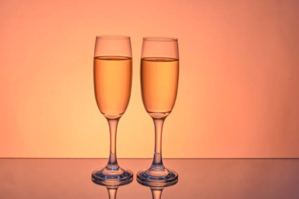 Two glass of wine isolated on color background, reflected in mirror.