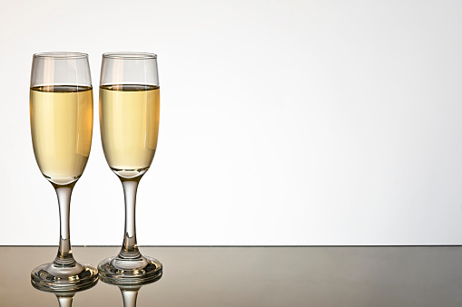 Two wine glass isolated on white color background, reflected in mirror.
