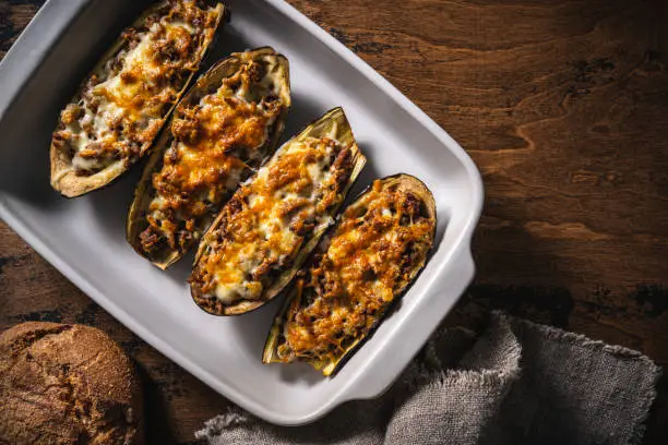 Stuffed Eggplants with minced meat recipe italian Aubergine Parmigiana or Eggplant parmesan on rustic wood table in an oven tray