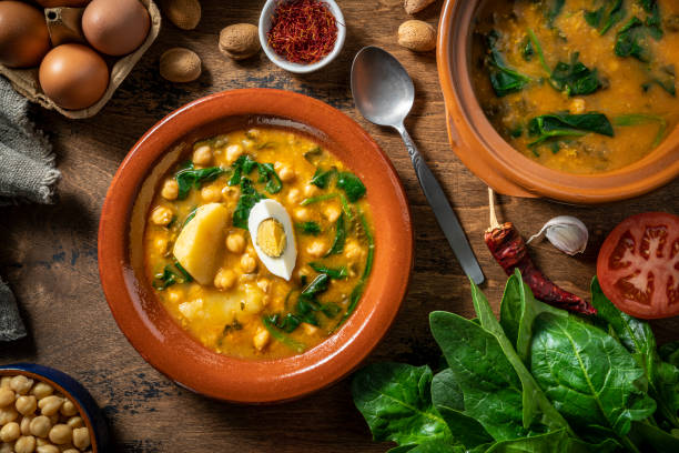 Potaje de garbanzos, chickpea stew spanish recipe vegetarian with spinach, potatoes and egg mediterranean diet on rustic wood