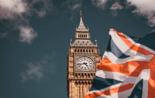 flag of UK waving in front of Big Ben and Westmister Abbey  London  UK stock photo