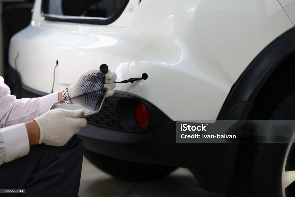 Mechanic installs parking sensors on car closeup Mechanic installs parking sensors on car. Checking parking sensors on car concept Parking Lot Stock Photo