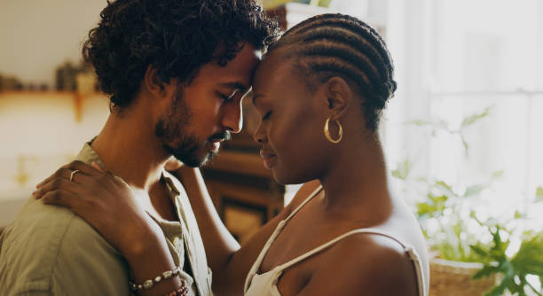 shot of a young couple standing together and sharing an intimate moment at home - couple african descent loving young adult imagens e fotografias de stock