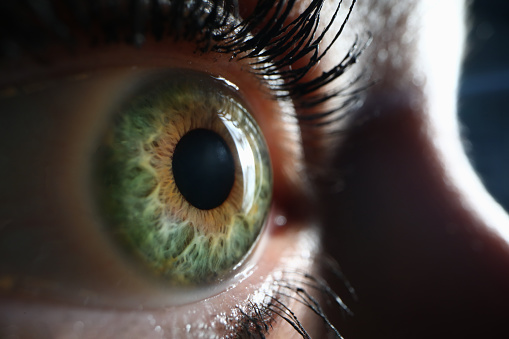 Close up on teenager boy's smiling eyes, green brown color with cross-eyed