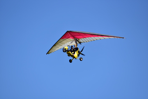 A two-seater kite flies in the clear sky