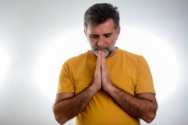 istock Mature man with eyes closed and hands clasped 1366636887