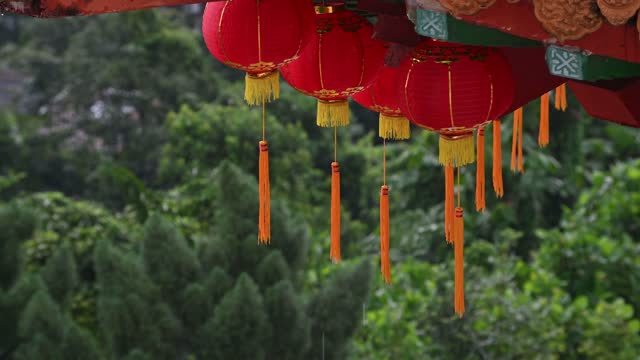 Round red lantern hanging on old traditional temple during raining day
