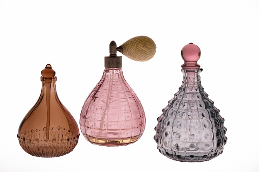 Transparent perfume bottle on a wooden round podium with sunlight and shadows of jasmine leaf flowers