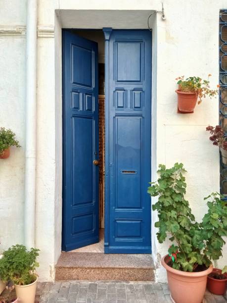 White facade and blue door with flower pots. Mediterranean village White facade and blue door with flower pots. Mediterranean village blue house red door stock pictures, royalty-free photos & images