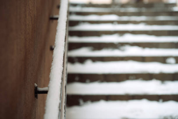 Stair railing and blurred staircase covered with snow.