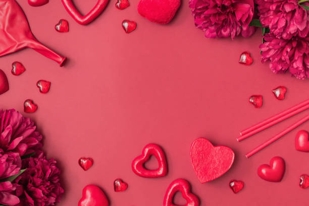 istock Flat lay valentines day frame with red peonies, paper drinking straws and red hearts on a red background. Valentines day banner with copy space 1366642762